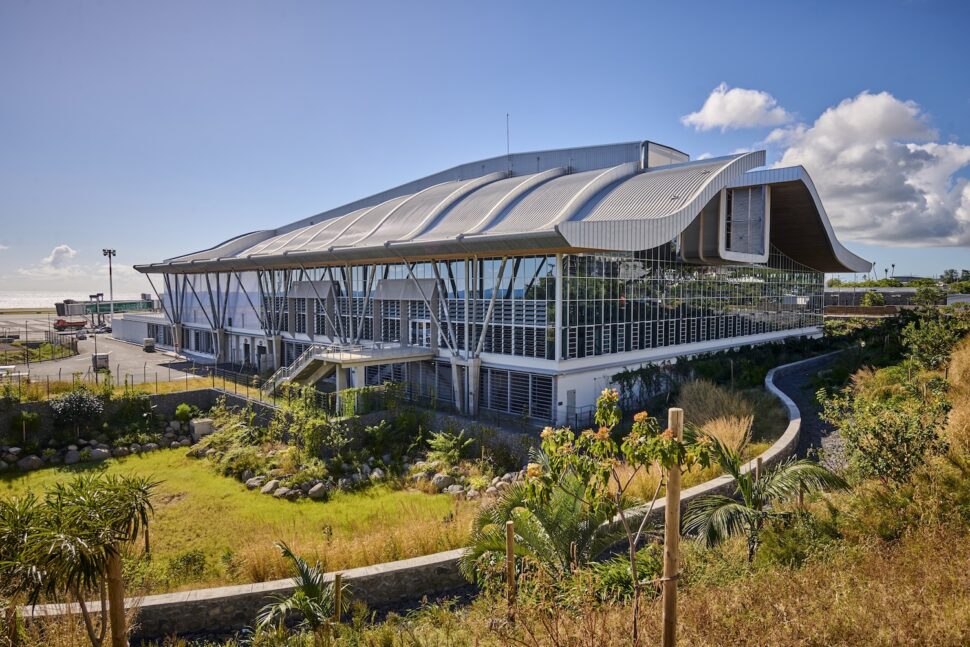Vue extérieure d'un aérogare à l'architecture moderne en milieu tropical, entouré de végétation luxuriante